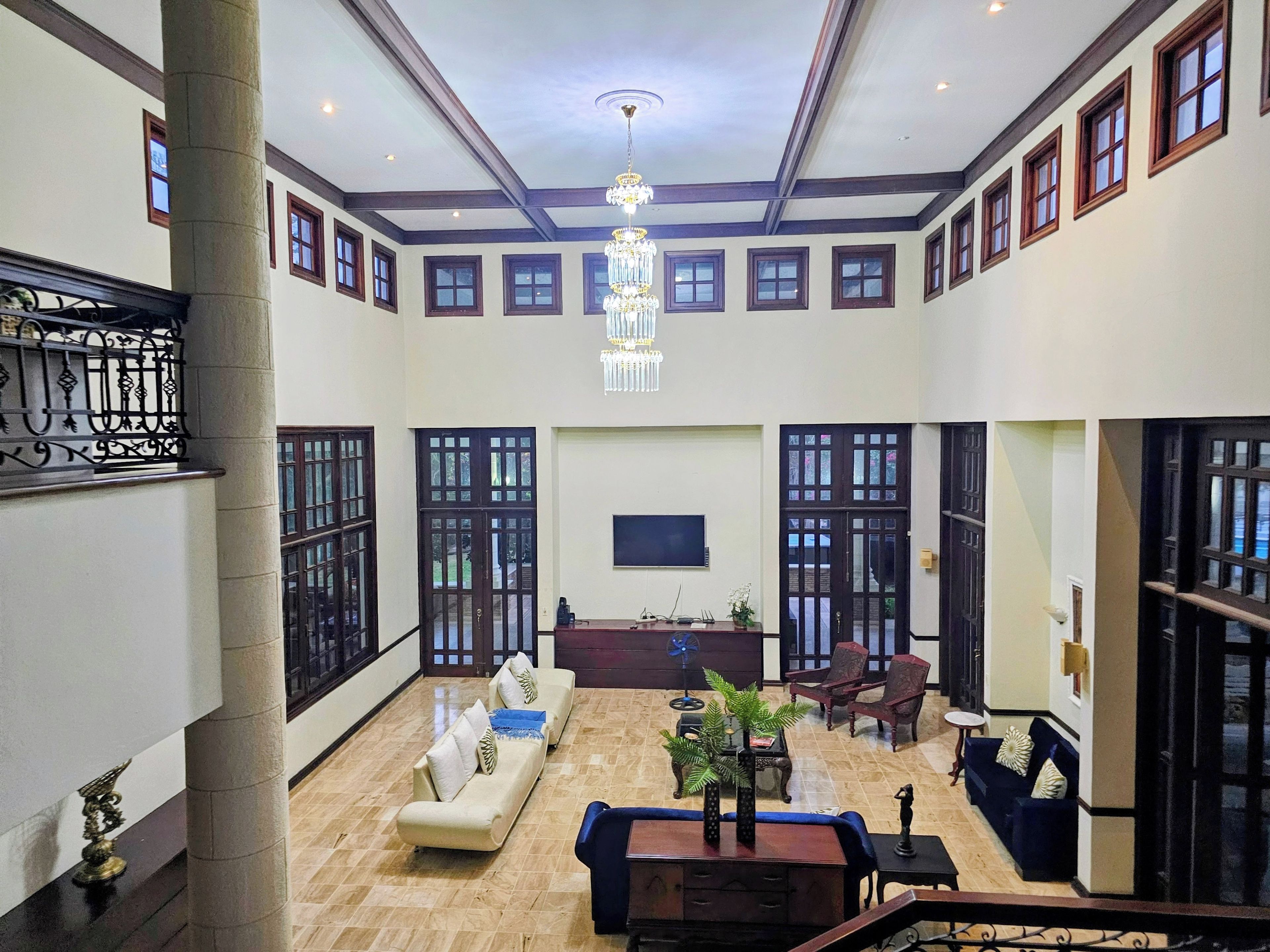 A spacious lobby with a high ceiling, a chandelier, a reception desk, and seating areas.