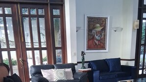 Ein geräumiger Wohnbereich mit großem Fenster, einem blauen Sofa, einem braunen Sessel und einem gemusterten Teppich.