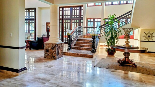 Eine großzügige Lobby mit Marmorboden, einer Treppe und großen Fenstern, die für viel Tageslicht sorgen.
