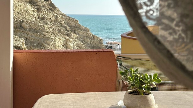 A balcony with a view of the sea, a potted plant, and a table. - Scala dei Turchi Apartments Villa Saporito (Lido Rossello)