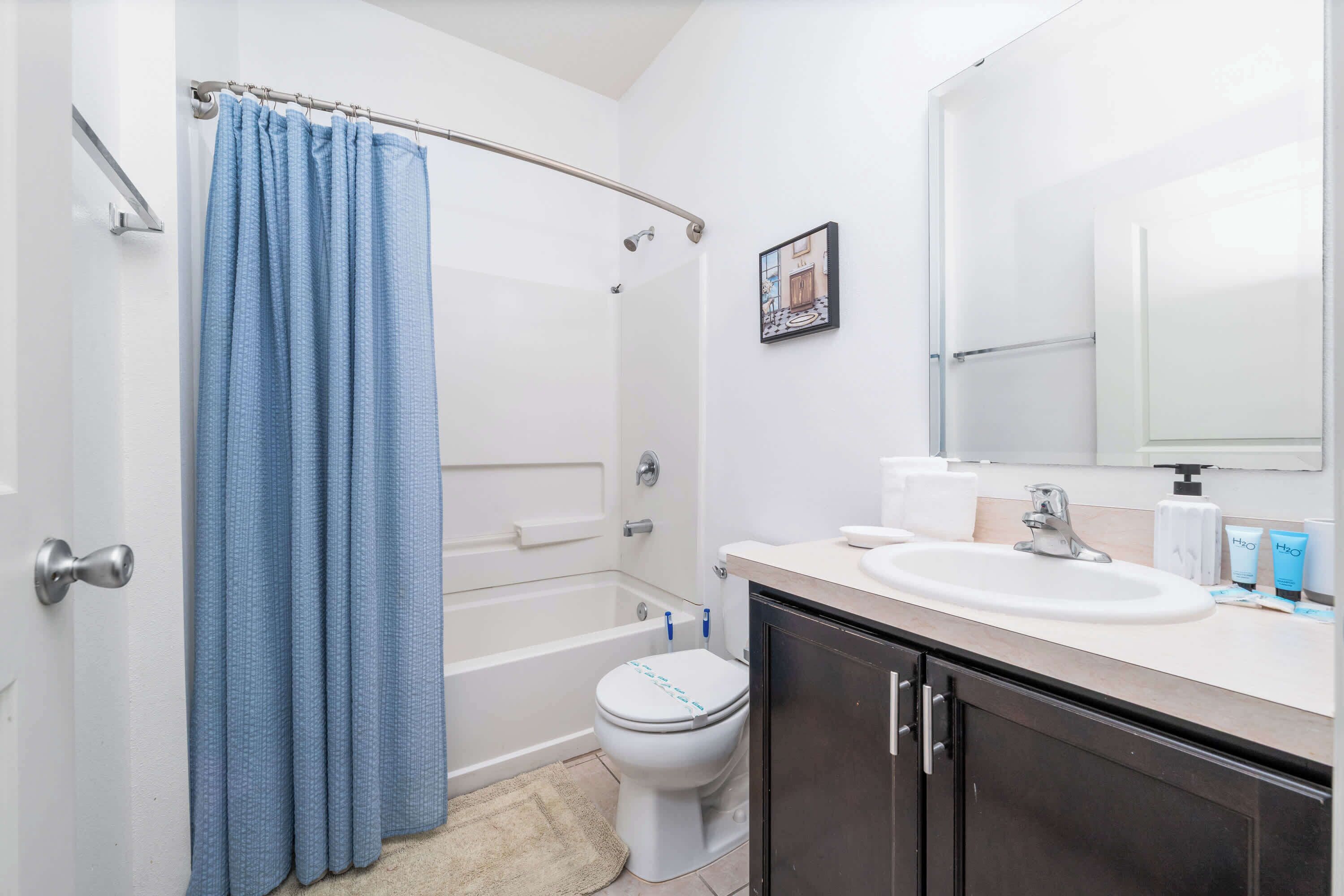 Een badkamer met een bad, toilet, wastafel en donkere kastjes.