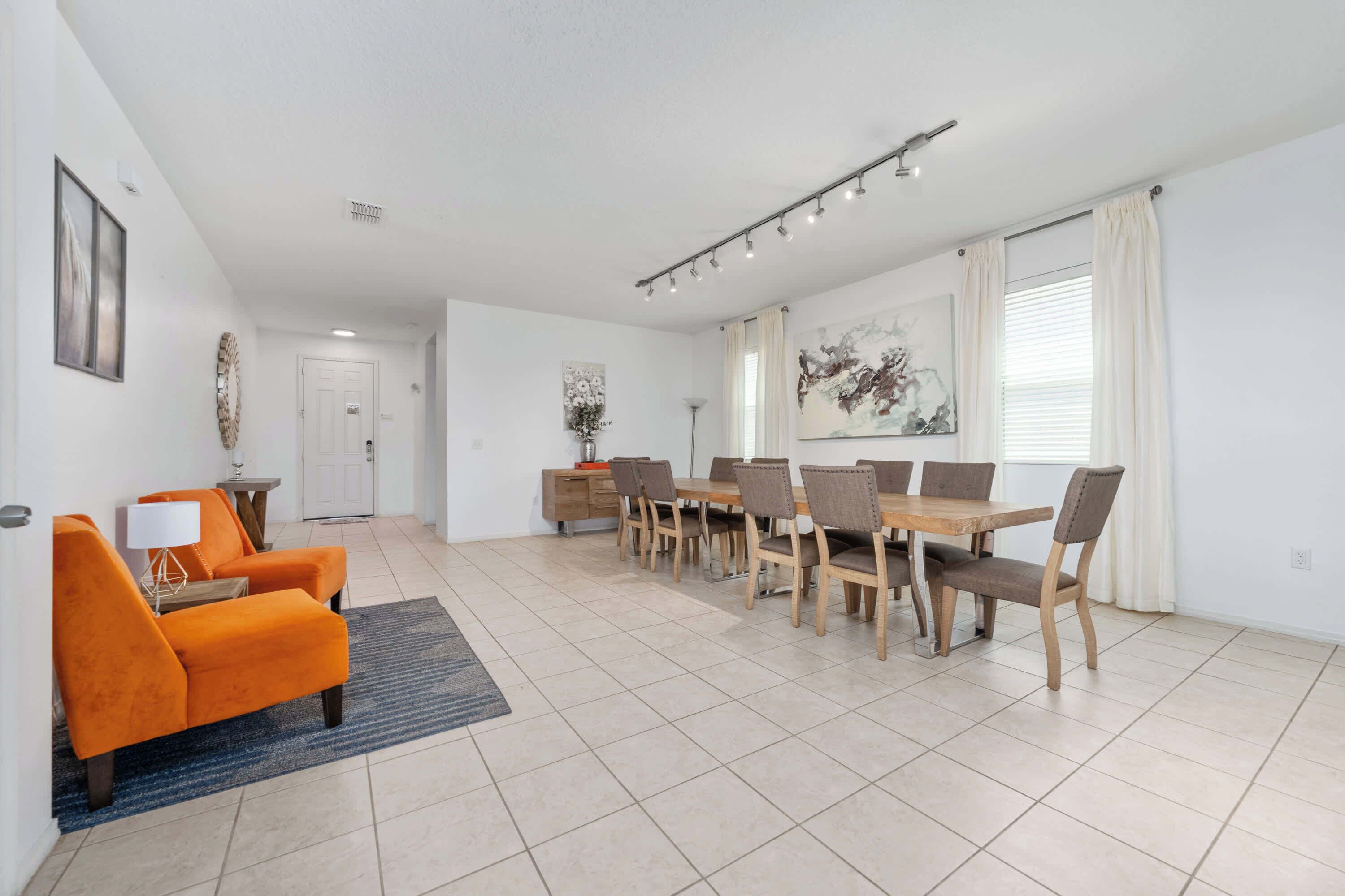 A modern dining area with a long table and chairs, a sofa, and a lamp.