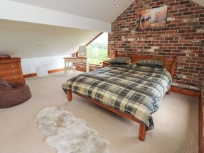 A bedroom with a bed, wooden dresser, desk, chair, and a large window. - Stagwood House (Holmfirth)