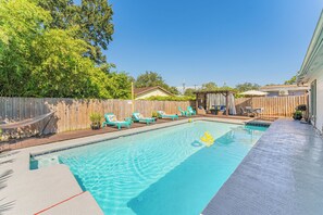 Ein Garten mit Pool, Liegestühlen und einer Holzterrasse.