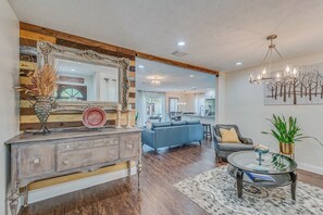 A living room with a wooden console, a mirror, a sofa, a coffee table, and a chandelier. - Gathering Place Pool home Tampa/USF Bush Garden, Adventure Island and Moffit (Tampa)