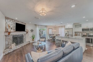 A spacious living room with a fireplace, a dining area, and a kitchen with modern appliances. - Gathering Place Pool home Tampa/USF Bush Garden, Adventure Island and Moffit (Tampa)