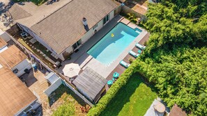 Een woonhuis met een zwembad, terras en een verzorgde tuin.