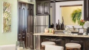 Eine Küche mit dunklen Holzschränken, einem Edelstahl-Kühlschrank, einer Marmorarbeitsplatte und einer Bar mit Hockern.