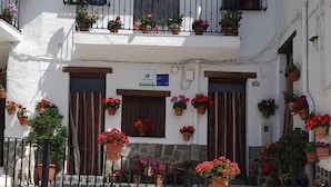 A white building with balconies adorned with potted flowers, a stone staircase, and a metal fence. - El Mirador Alto Apartment (Trevélez)