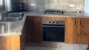A kitchen with wooden cabinets, a gas stove, a dishwasher, and a sink. - El Mirador Alto Apartment (Trevélez)