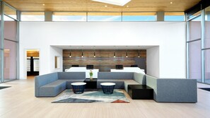 Een moderne lobby met een hoekbank, twee zwarte tafels en een behang met een patroon.
