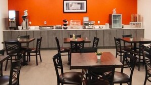 Un restaurant avec des tables et des chaises, un comptoir où est affiché le menu, et un tableau encadré au mur.