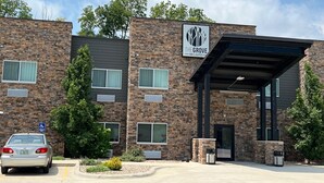 Un bâtiment doté d’une façade en pierre, d’une entrée abritée et d’un panneau indiquant les places de stationnement réservées aux personnes handicapées.