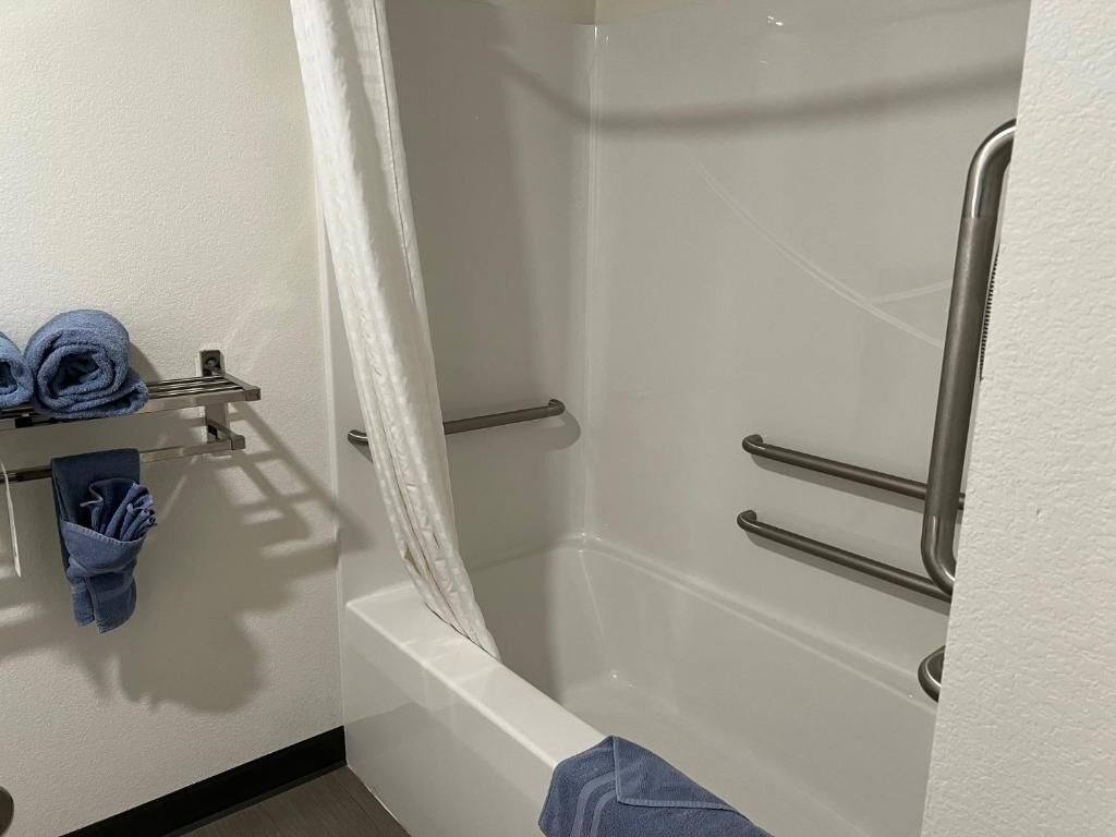 A bathroom with a bathtub, a shower area, and a towel rack with towels.