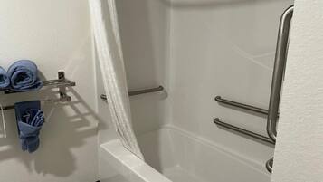 A bathroom with a bathtub, a shower area, and a towel rack with towels.