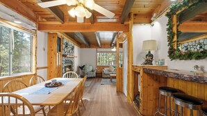 Un interior de madera con zona de comedor, taburetes de bar y chimenea.