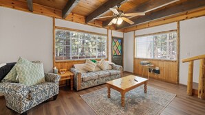 Un interior de madera con sofá, sillón, mesa de centro y ventilador de techo.