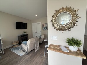 A living room with a TV, a fireplace, a sofa, a coffee table, and a decorative mirror.
