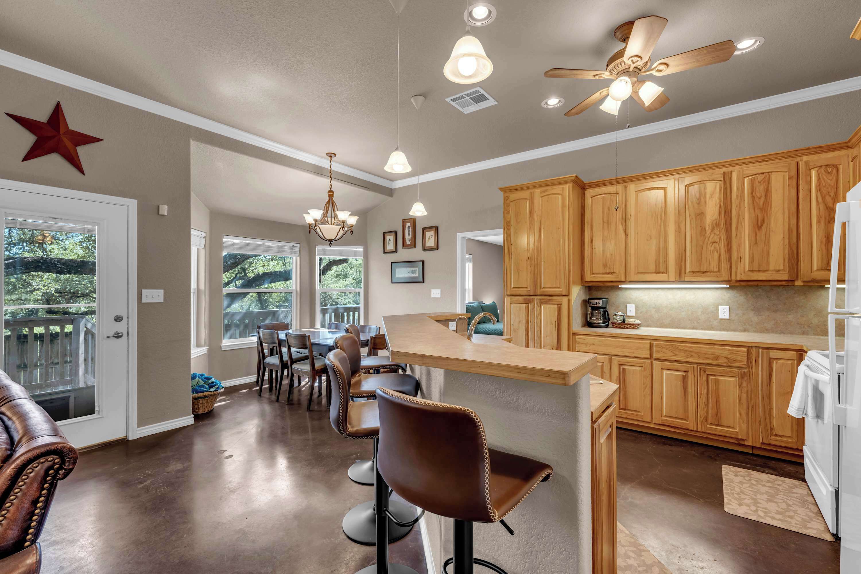 A spacious kitchen with wooden cabinets, a bar area, and a dining space with chairs.