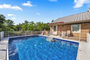 A swimming pool with a metal deck, a white fence, and a building with a metal roof in the background. - Pop's Place: Private Pool & Lake Access! (Granite Shoals)
