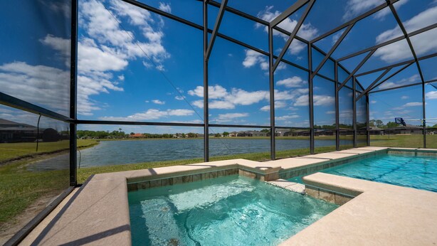 Piscina com vista para um lago, rodeada por um compartimento de vidro.