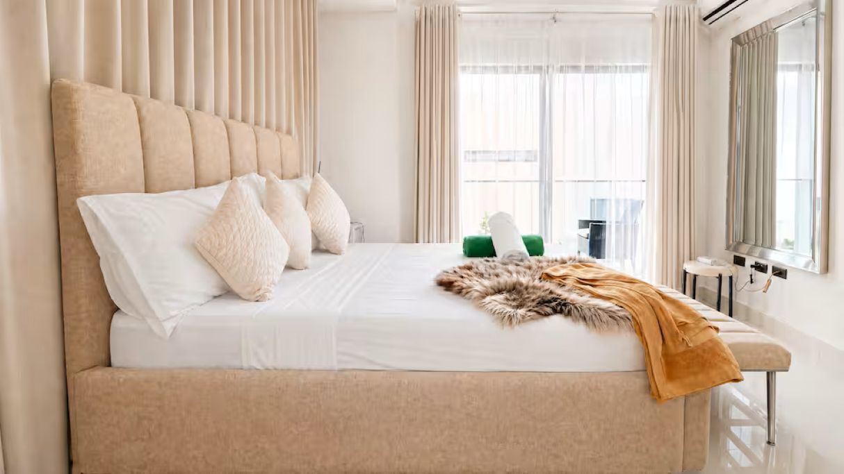 A bed with a headboard, pillows, a blanket, and a fur throw.