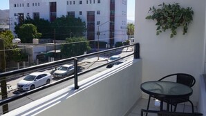 A balcony with a table and chairs, overlooking a street with parked cars and a white building in the background. - Central Zone Department (La Paz)