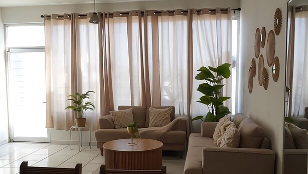 A living room with a sofa, coffee table, and chairs, a ceiling fan, and a large window with curtains. - Central Zone Department (La Paz)
