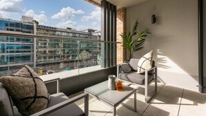 A balcony with a sofa, a coffee table, and a plant. - Apex Executive Apartments - The Benson (Dublin)