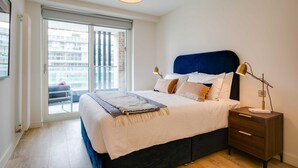 A bedroom with a bed, bedside table, lamp, and a view through a sliding door to an outdoor balcony. - Apex Executive Apartments - The Benson (Dublin)