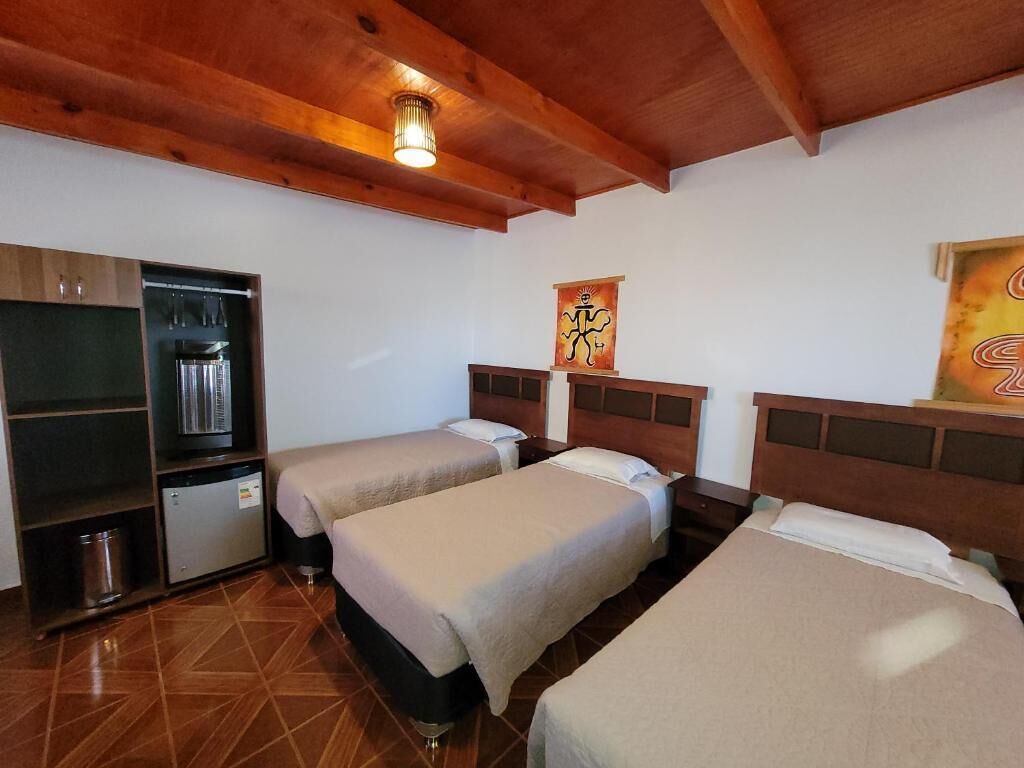 A room with two beds, a small refrigerator, a cabinet, and a ceiling light fixture.