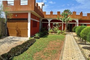 A building with a brick facade, a gated entrance, and a paved pathway leading to a covered walkway. - Private Beach House Fidjrosse, 2 Steps to the Ocean (Cotonou)