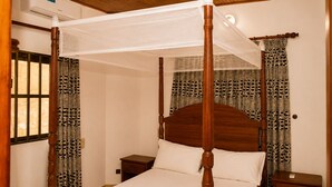 A four-poster bed with a canopy, wooden headboard, and nightstands.