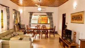 A living room with a sofa, dining table, chairs, and a TV.