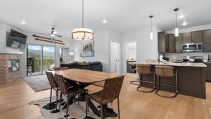 Una cocina moderna con una isla central, taburetes de bar y un comedor con una mesa y sillas de madera.