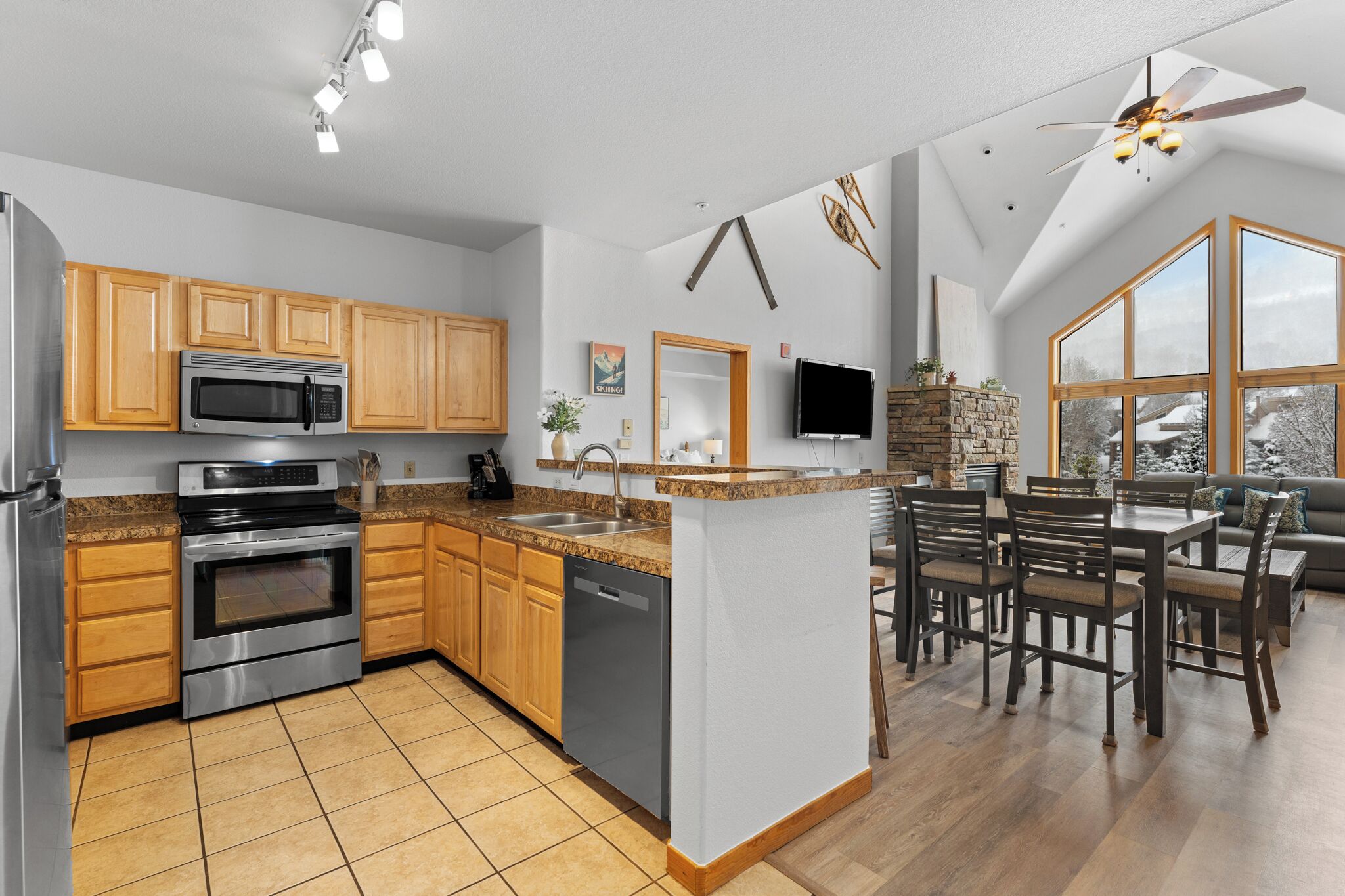 A modern kitchen with wooden cabinets, stainless steel appliances, and a dining area with a large island and seating.