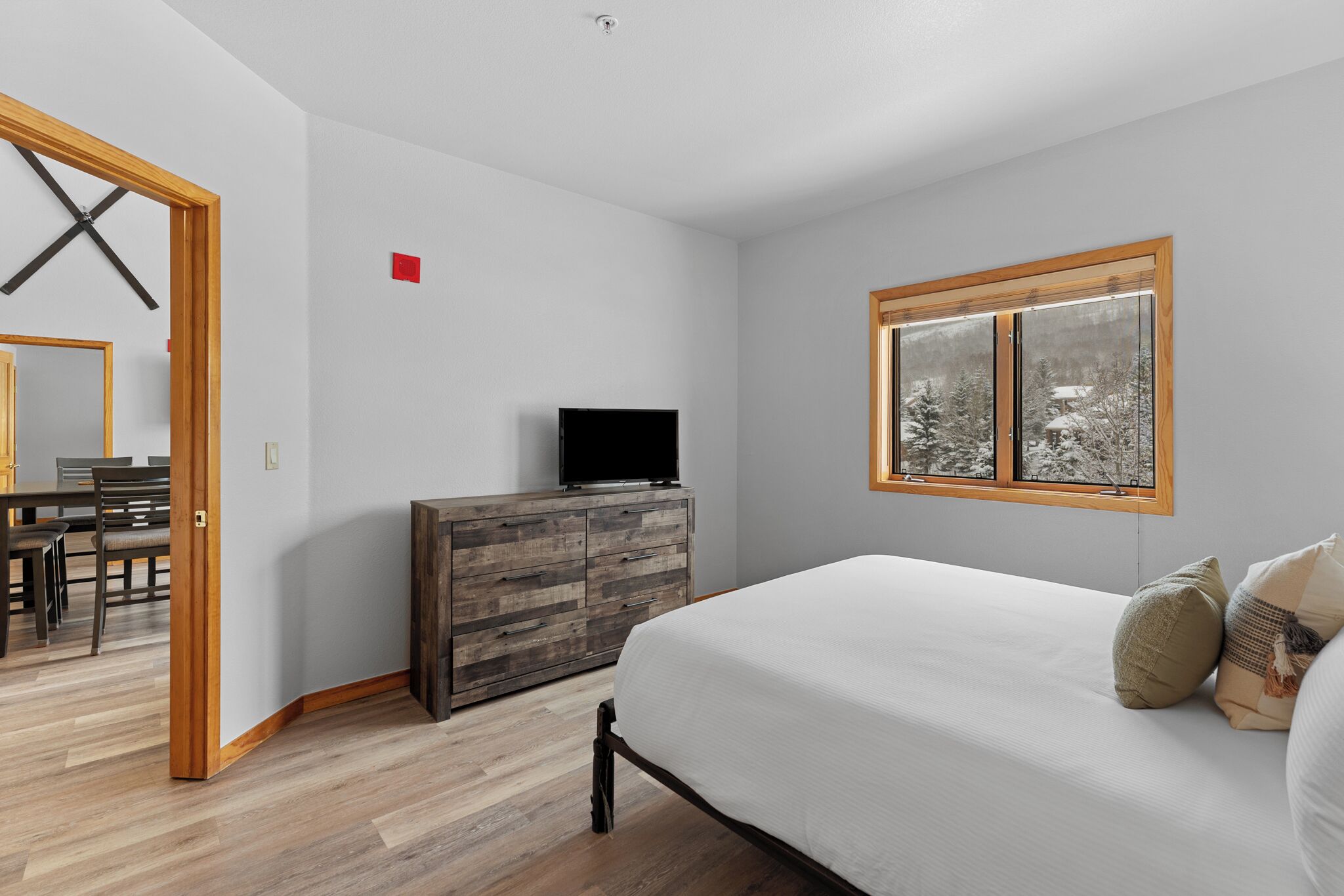 Un dormitorio con cama, cómoda, televisor y ventana con vistas.