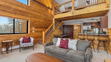 Ein Holzblockhaus-Interieur mit Wohnbereich, Treppe und Küche.