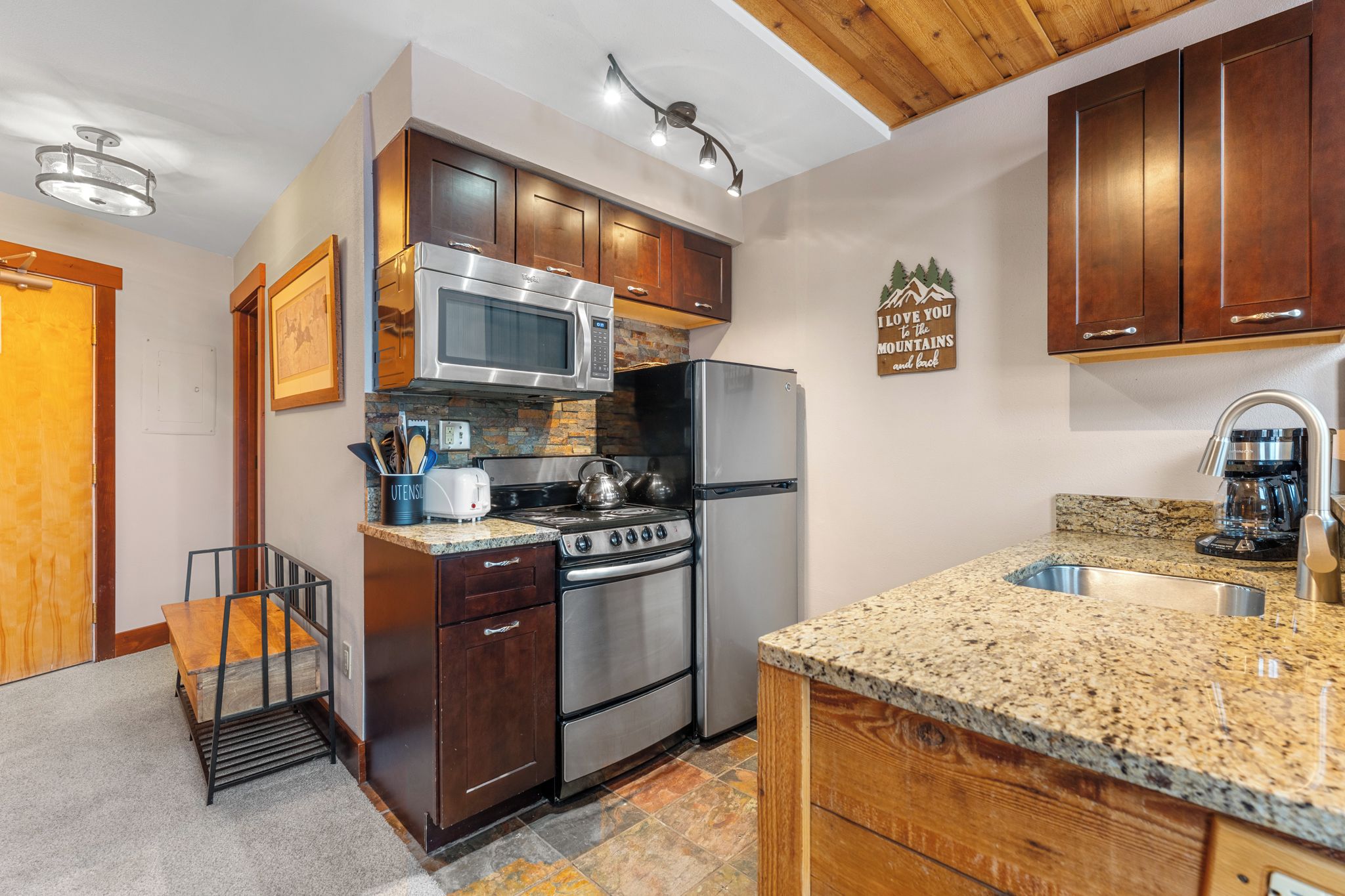 A kitchen with wooden cabinets, stainless steel appliances, granite countertops, and a built-in stove.