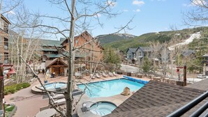 Ett semesterhotell med en swimmingpool, solstolar och utsikt över bergen.