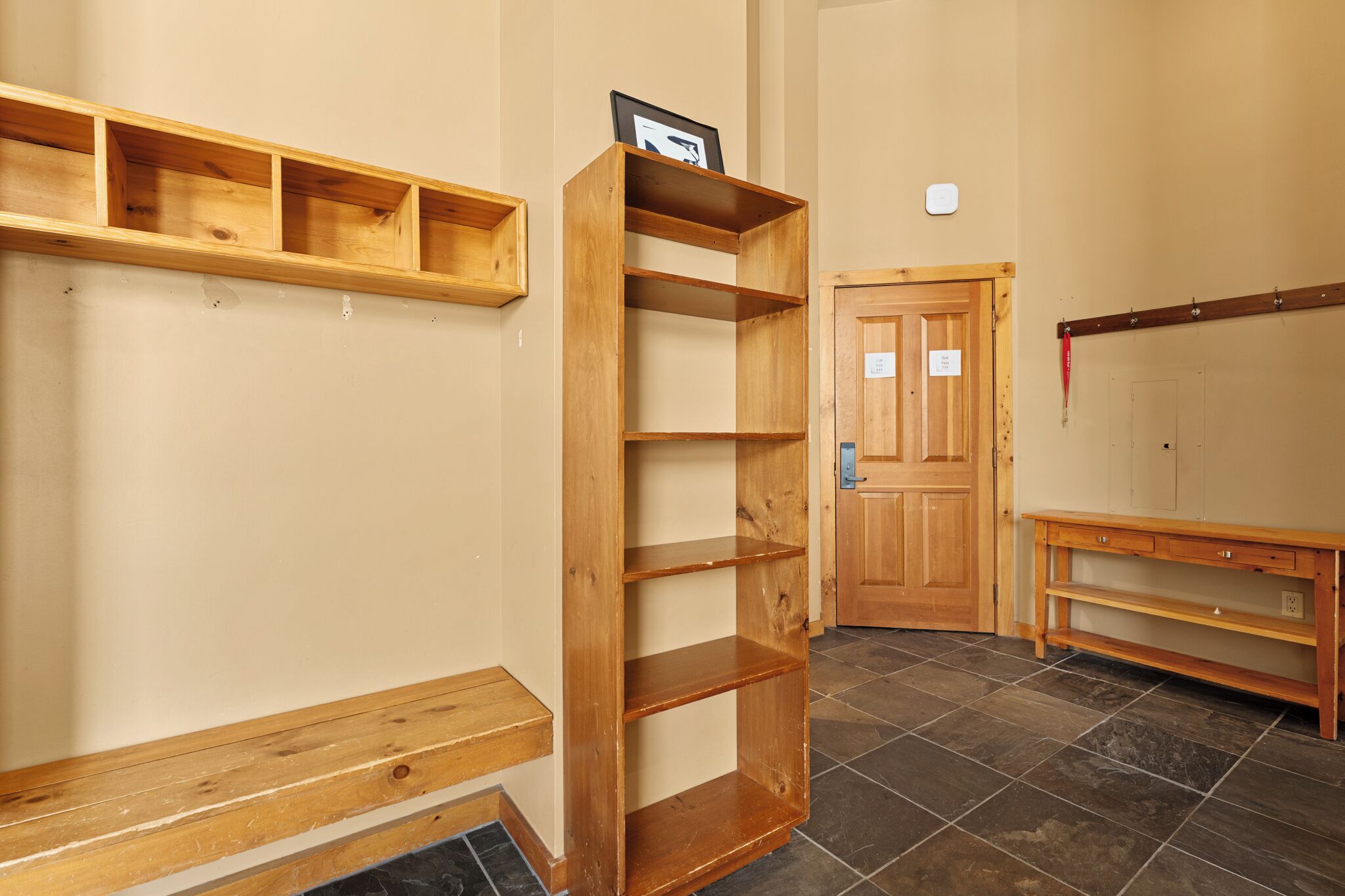 Ein Zimmer mit einem Bücherregal aus Holz, einer hölzernen Bank und einer Tür.