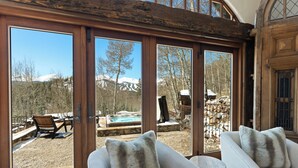 Une pièce dotée de grandes portes-fenêtres coulissantes, d’un canapé recouvert d’un plaid en fausse fourrure et offrant une vue sur une montagne et un jacuzzi à l’extérieur.