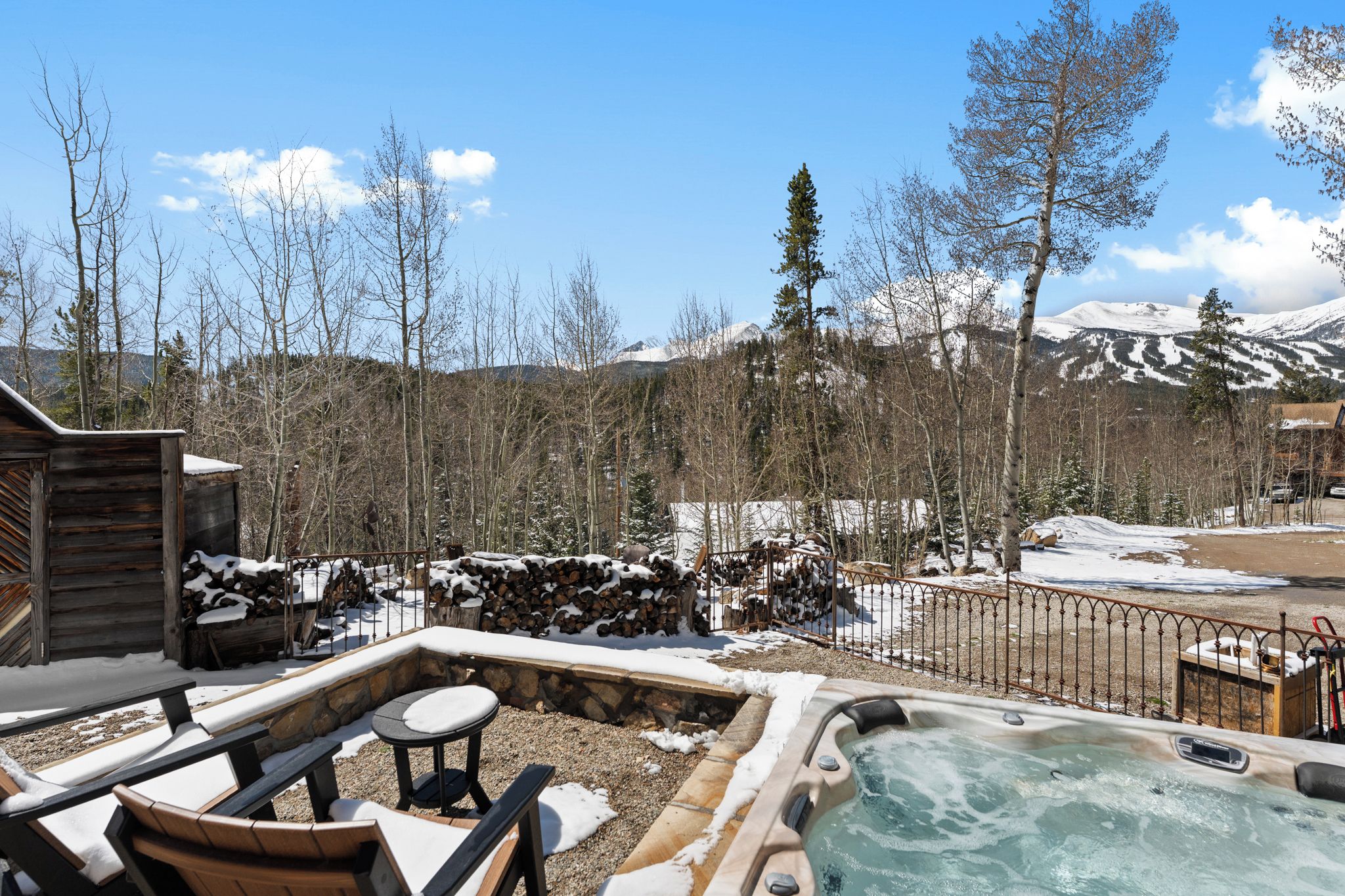 A hot tub, outdoor seating, and a view of snow-covered mountains.
