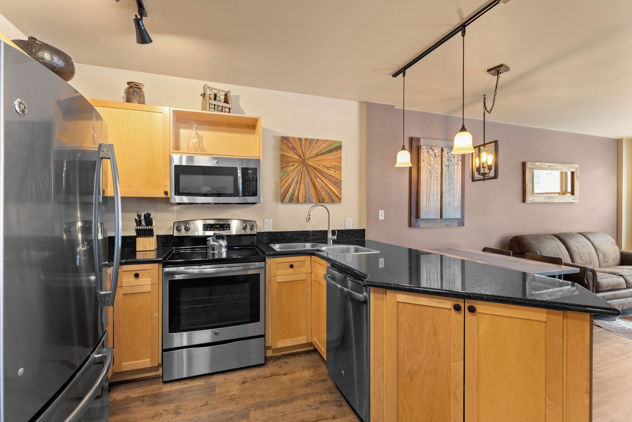 A modern kitchen with stainless steel appliances, wooden cabinets, and a black countertop.