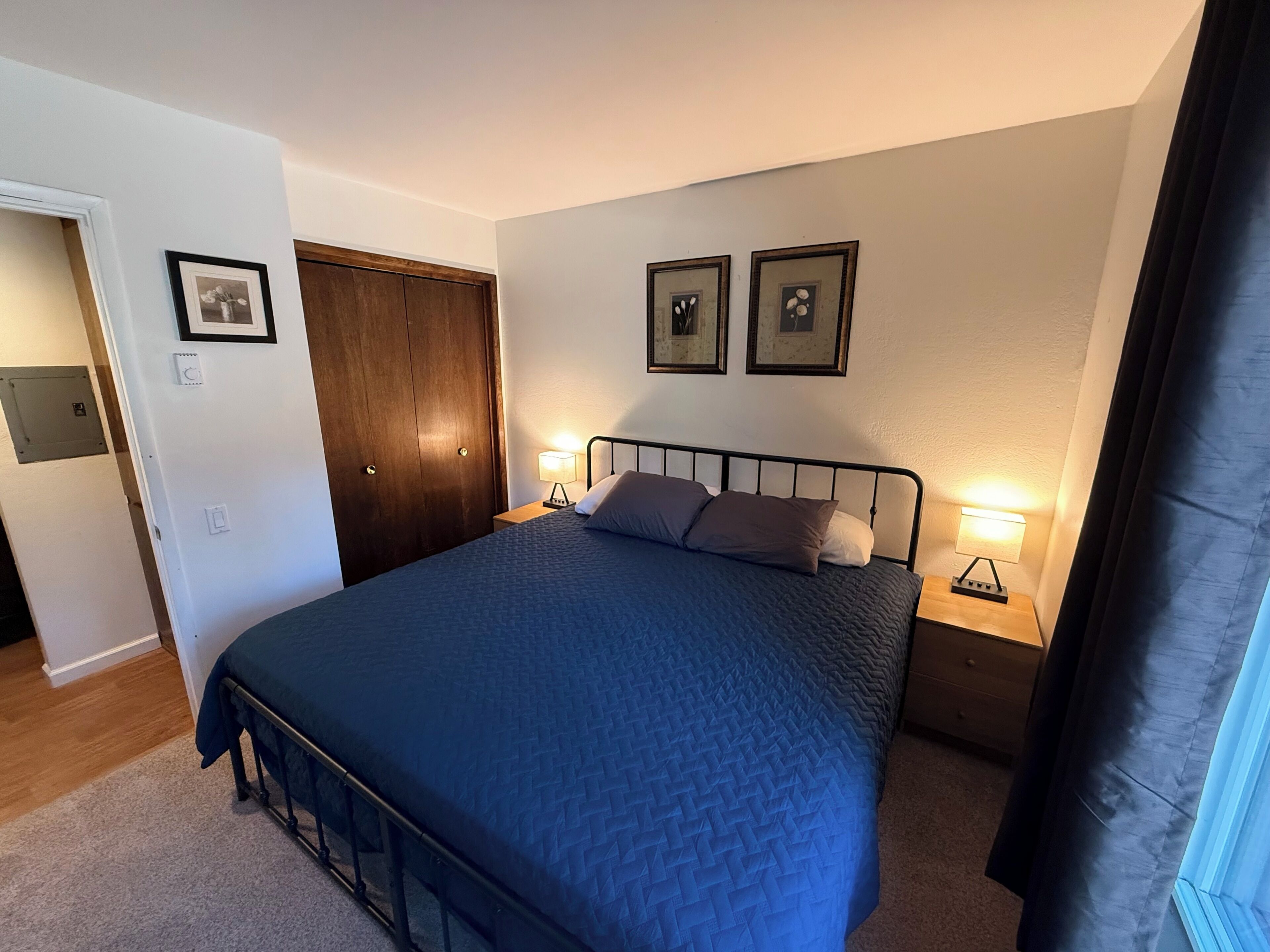 Une chambre à coucher avec un lit, des lampes de chevet, une armoire et des tableaux encadrés accrochés au mur.