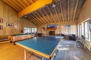 A billiards room with two tables, a fireplace, and a stone wall. - Sunshine Loft ~ Free Shuttle ~ Pool & Hot Tub (Mammoth Lakes)