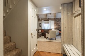 Ein Flur, der in ein Wohnzimmer mit Kamin, einer Treppe und einer Tür führt.