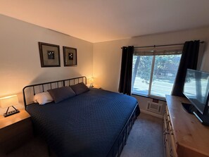 A bedroom with a bed, bedside tables, a TV, and a window with curtains. - Sunshine Loft ~ Free Shuttle ~ Pool & Hot Tub (Mammoth Lakes)