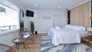 A bedroom with a bed, two wicker chairs, a television on the wall, and a door. - SIngle Room - 1 King Bed -Valley View (Himrod)