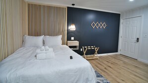 Une chambre d’hôtel comprenant un lit, une table de chevet, une lampe et un élément décoratif fixé au mur.